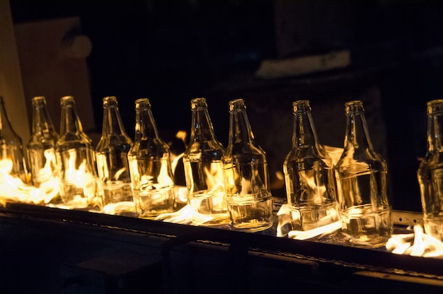 Usine de production de bouteilles en verre. bouteilles en verre sur un tapis roulant avec feu