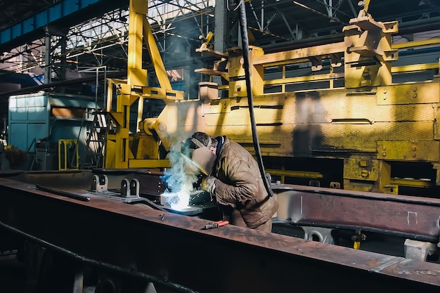 Usine de train avec soudeur pendant le travail sur les pièces de rechange en fer