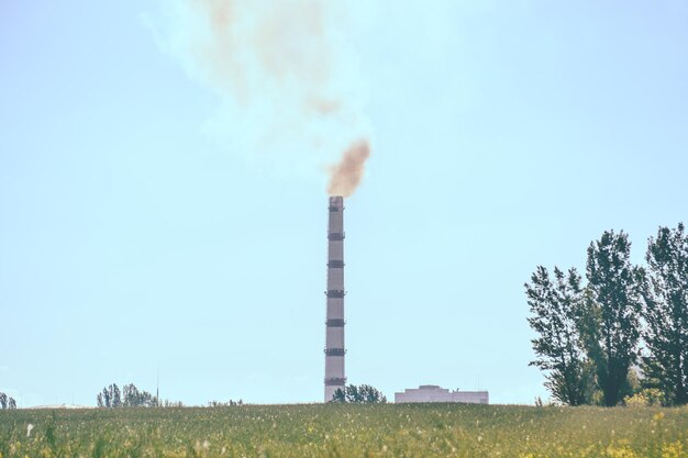 Usine de tuyaux fumée sur le terrain avec ciel clair