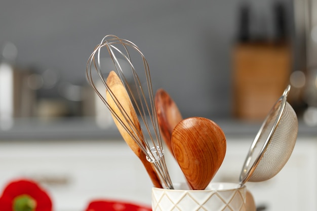 Ustensiles de cuisine dans une tasse sur la table de cuisine close up