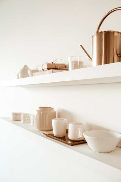 Ustensiles de cuisine sur étagère sur blanc. Tasses en céramique, tasses, théière, plateau.