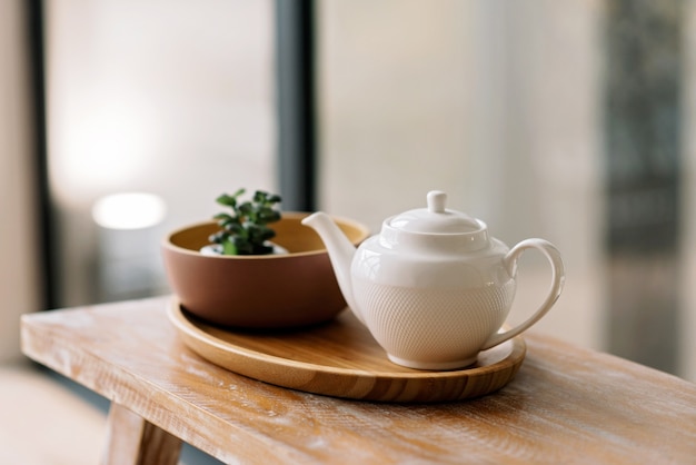 Ustensiles de cuisine, tels que bouilloire, cafetière, sur un plateau en bois. Petit déjeuner matinal. Mise au point sélective douce.