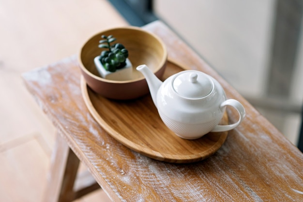 Ustensiles de cuisine, tels que bouilloire, cafetière, sur un plateau en bois. Petit déjeuner matinal. Mise au point sélective douce.