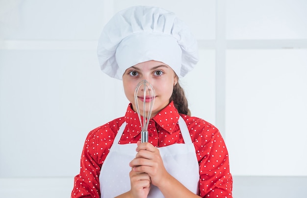 Utilisation d'un batteur pour la cuisson. école culinaire. la cuisine traditionnelle. enfant s'amusant à la cuisine. Enfant et pâtisserie. Concept d'alimentation saine et de mode de vie. fille faisant de la pâte à l'aide d'un batteur. régime et santé.