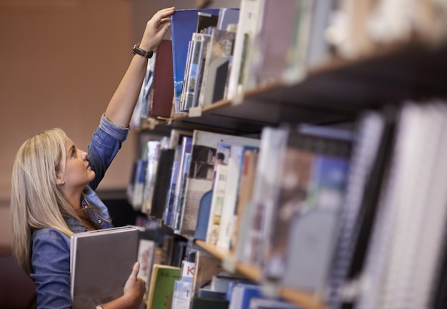 Utilisation de la bibliothèque du campus Photo d'un jeune étudiant dans une bibliothèque