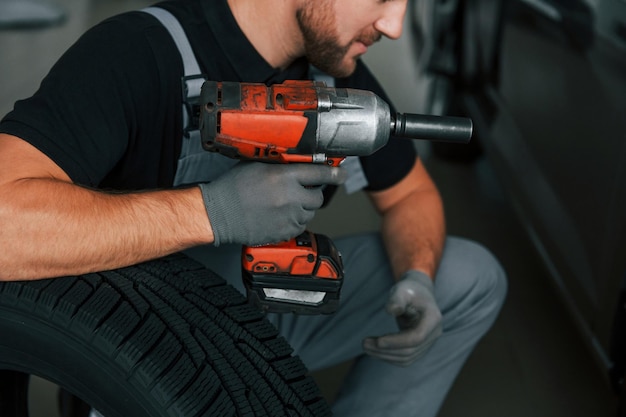 Utilisation de l'équipement L'homme en uniforme travaille dans l'autosalon pendant la journée