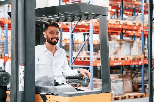 Utilisation d'une machine de déménagement de fret Le travailleur du stockage est dans l'entrepôt avec un tas de produits