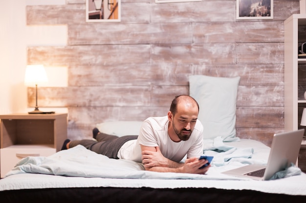 Utilisation d'un smartphone allongé sur le lit la nuit