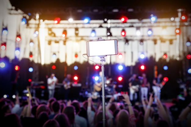 Photo utilisation d'un smartphone sur une perche à selfie lors d'un spectacle musical écran blanc vide vide pour votre image