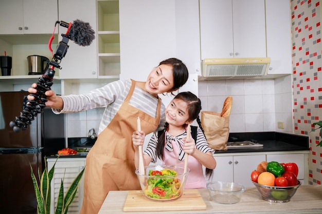 Utilisation de la technologie à la maison Diffusion en direct d'une mère et d'une fille pour cuisiner une salade de légumes