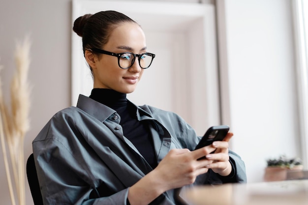 Utilise le gestionnaire de téléphone indépendant Femme portant des lunettes bureau de travail