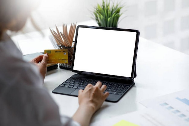 Utiliser à la main un ordinateur portable avec un écran blanc vide dans un café
