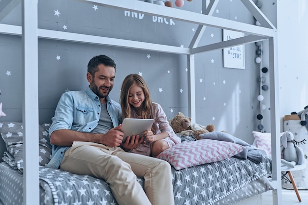 utiliser les technologies pour le plaisir. jeune père et sa petite fille regardant une tablette numérique