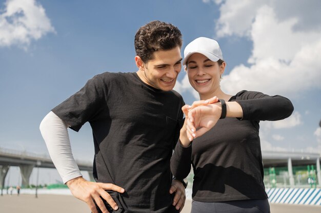 Utilisez une application de fitness une montre-bracelet au bras Homme et femme Un couple heureux en vêtements de sport