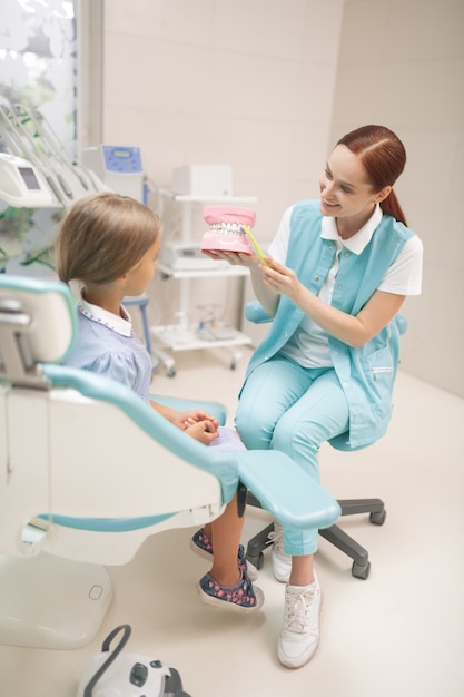 Utilisez une brosse à dents. Fille écoutant un dentiste lui montrant comment utiliser une brosse à dents deux fois par jour