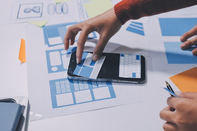 UX UI designer testing prototype on a phone discussing and brainstorming on wireframes for a website and mobile app prototype in the concept of website and mobile application design concept