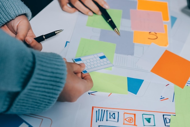 UX UI designer testing prototype on a phone discussing and brainstorming on wireframes for a website and mobile app prototype in the concept of website and mobile application design concept