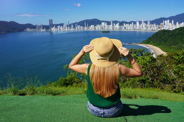 Vacances au Brésil Traveler girl sitting on viewpoint profitant de l'horizon de Balneario Camboriu sur l'océan Atlantique Brésil