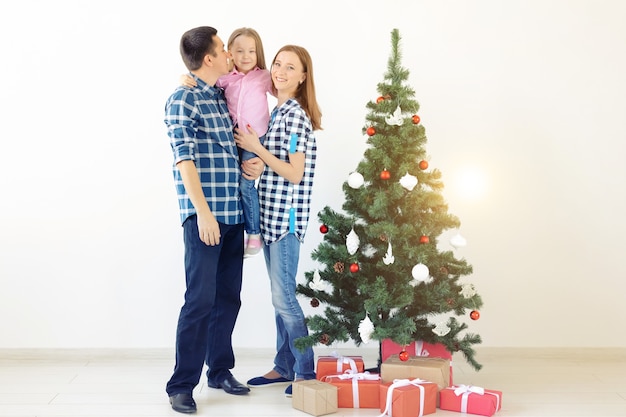 Vacances, cadeaux et concept d'arbre de Noël - Petite famille s'amusant ensemble à Noël