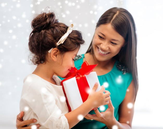vacances, cadeaux, noël, concept x-mas - heureuse mère et enfant fille avec boîte-cadeau sur fond neigeux