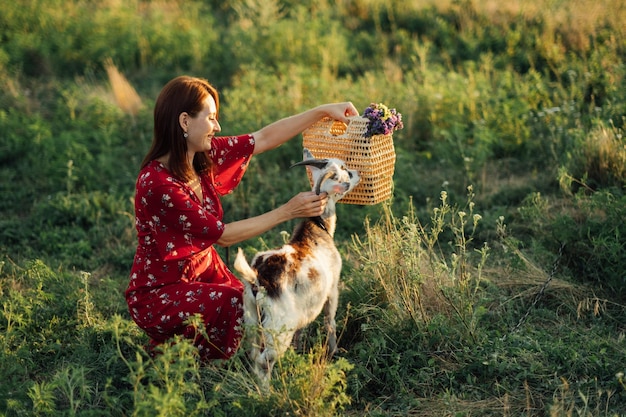 Vacances à la campagne Séjours et escapades à la campagne Pause détente à la campagne dans un gîte rural Femme en robe nourrissant des chèvres sur la pelouse