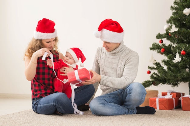 Vacances, enfants et concept de famille - Couple heureux avec bébé célébrant Noël ensemble à la maison.