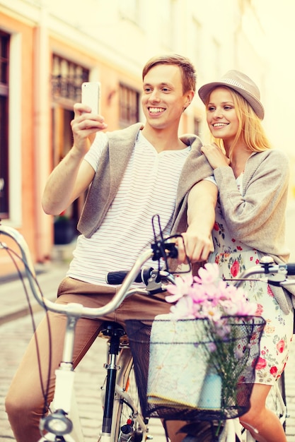 vacances d'été, amour, navigation, gps et concept de rencontres - couple souriant avec vélos et smartphone dans la ville