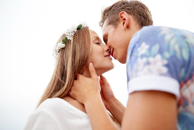 vacances d'été, amour, romance et concept de personnes - heureux souriant jeune couple hippie s'embrassant à l'extérieur