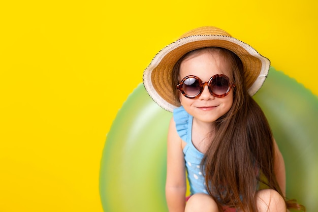 Vacances d'été au bord de la mer Une jolie fille à lunettes de soleil et un maillot de bain fond jaune