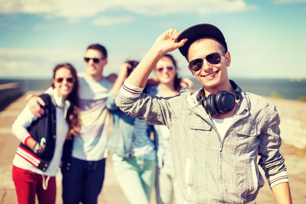 vacances d'été et concept adolescent - adolescent en lunettes de soleil, casquette et casque avec des amis à l'extérieur