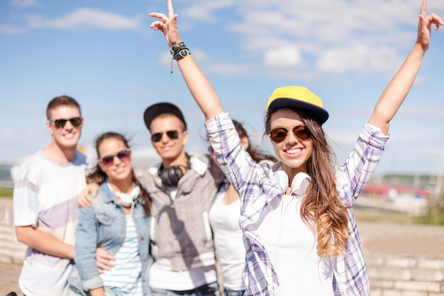 vacances d'été et concept d'adolescent - adolescente en lunettes de soleil, casquette et casque avec des amis à l'extérieur