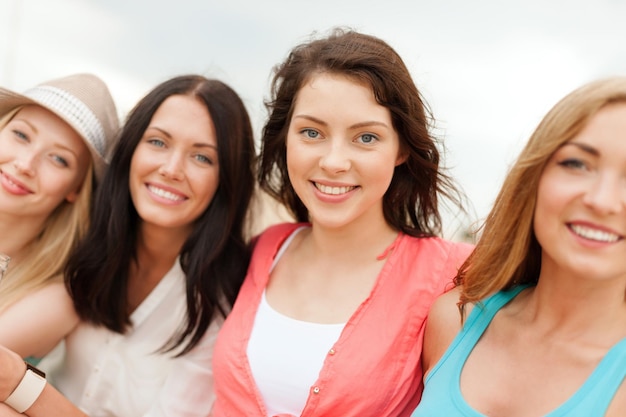 Photo vacances d'été et concept de vacances - groupe de filles souriantes se détendre sur la plage