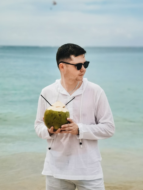 Vacances d'été jeune homme à lunettes de soleil se détendre sur la mer bleue et boire de la noix de coco. Belle vue sur la plage avec l'homme voyageur se détendre à Phuket, Thaïlande