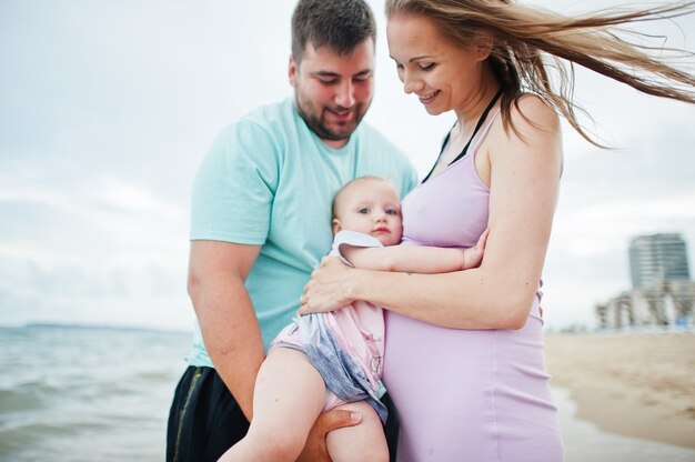 Vacances d'été. Parents et personnes activité de plein air avec les enfants. Bonnes vacances en famille. Père, mère enceinte, petite fille sur la plage de sable de la mer.