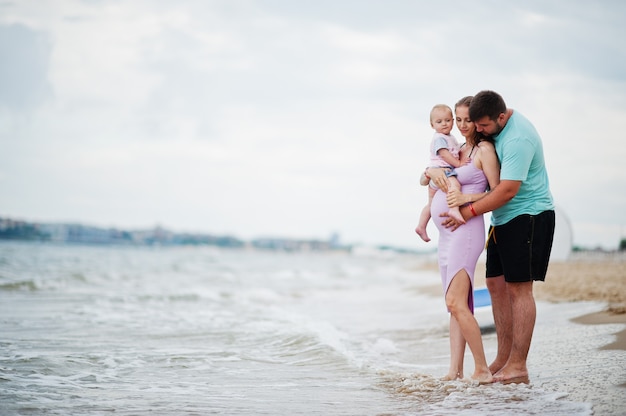 Vacances d'été. Parents et personnes activité de plein air avec les enfants. Bonnes vacances en famille. Père, mère enceinte, petite fille sur la plage de sable de la mer.