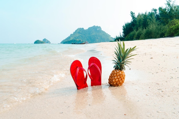 Vacances d'été à la plage avec des ananas et des tongs sur la plage