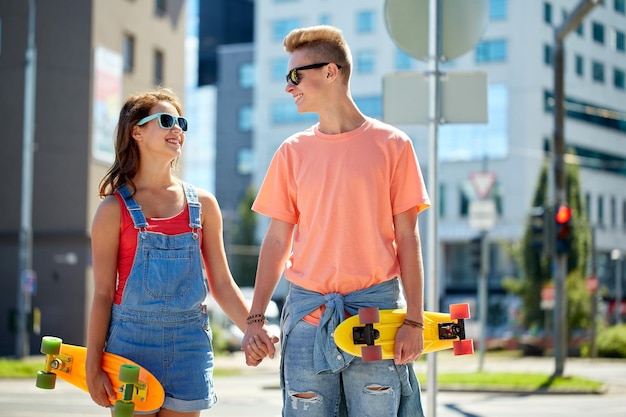 vacances d'été, sport extrême et concept humain - couple d'adolescents heureux avec de courtes planches à roulettes modernes sur la rue de la ville