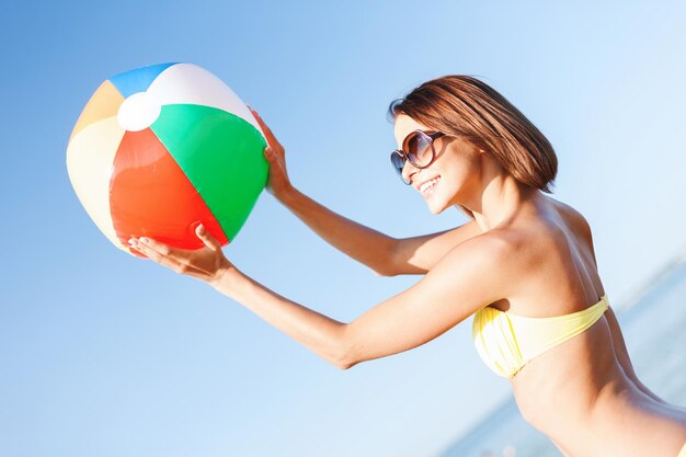 vacances d'été, vacances et activités de plage concept - fille en bikini jouant au ballon sur la plage