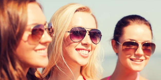 vacances d'été, vacances, amitié et concept de personnes - gros plan de jeunes femmes souriantes en lunettes de soleil