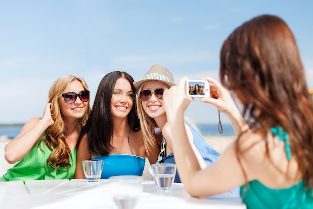 vacances d'été et vacances - filles prenant des photos avec un appareil photo numérique dans un café sur la plage