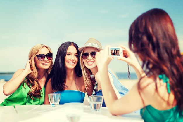 vacances d'été et vacances - filles prenant des photos avec un appareil photo numérique dans un café sur la plage