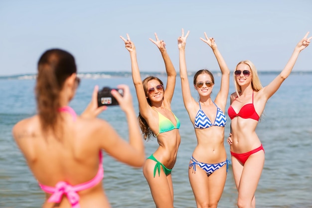 vacances d'été, vacances, geste et concept de personnes - groupe de femmes souriantes photographiant par caméra et montrant un soupir de paix sur la plage