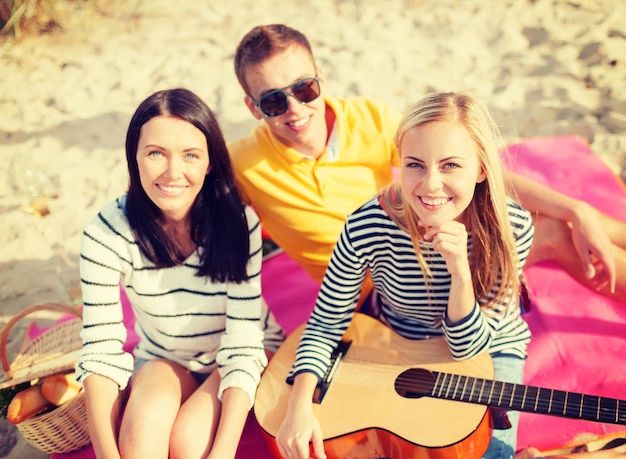 vacances d'été, vacances, musique, concept de gens heureux - groupe d'amis avec guitare s'amusant sur la plage