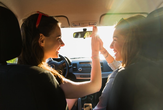 vacances d'été, vacances, voyage, voyage sur la route et concept de personnes - adolescentes ou jeunes femmes heureuses conduisant en voiture et faisant un geste de cinq