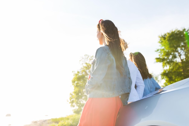 vacances d'été, vacances, voyage, voyage sur la route et concept de personnes - adolescentes ou jeunes femmes heureuses près de la voiture au bord de la mer