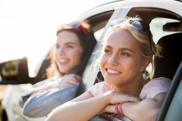 vacances d'été, vacances, voyage, voyage sur la route et concept de personnes - adolescentes ou jeunes femmes heureuses en voiture au bord de la mer