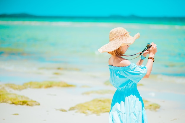 Vacances d'été voyage de vacances et concept de personnes jeune femme prendre une photo en chapeau de soleil sur la plage au-dessus de la mer et de l'espace de fond de ciel bleu