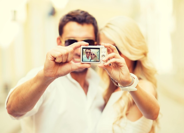 vacances d'été, voyage, vacances, tourisme et concept de rencontres - couple de voyageurs prenant une photo avec un appareil photo