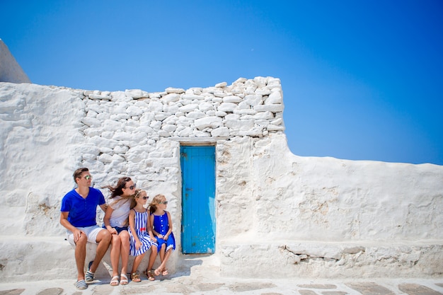 Vacances en famille en Europe. Parents et enfants dans la rue d'un village traditionnel grec typique avec des murs blancs et des portes colorées sur l'île de Mykonos, en Grèce
