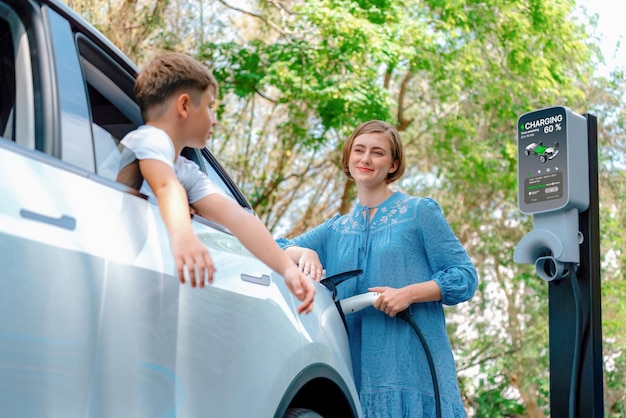 Vacances en famille avec véhicule électrique mère et fils recharger voiture électrique avec énergie verte et propre Nature et voyager avec voiture écologique pour un environnement durable Perpetuel